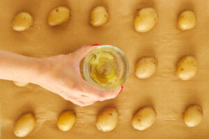 A cup flattening potatoes on a baking sheet.