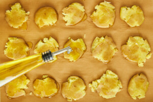 Boiled potatoes being topped with olive oil.