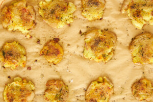 Baked crispy potatoes on a parchment-lined baking sheet.