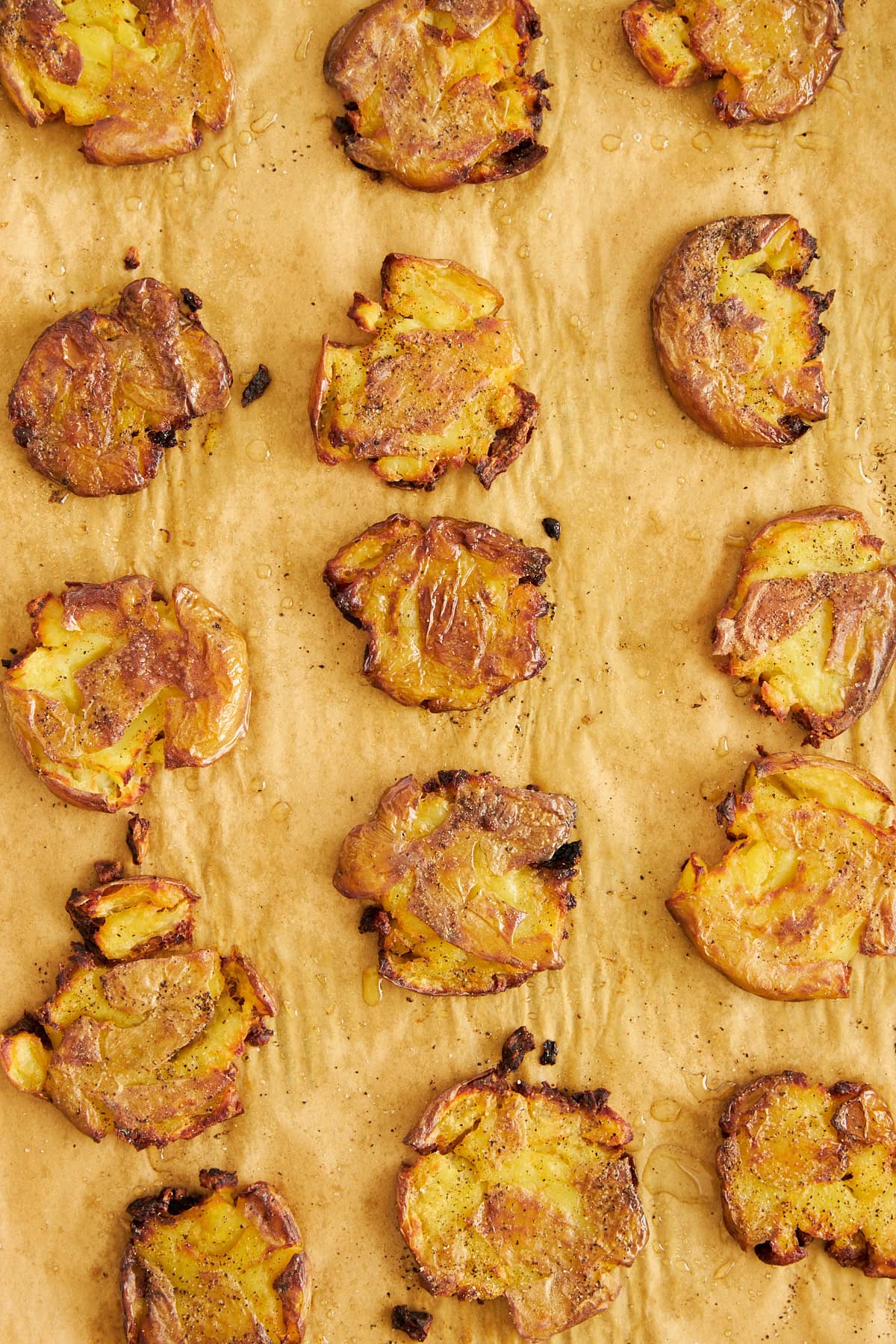 Baked crispy potatoes on a parchment-lined baking sheet. 