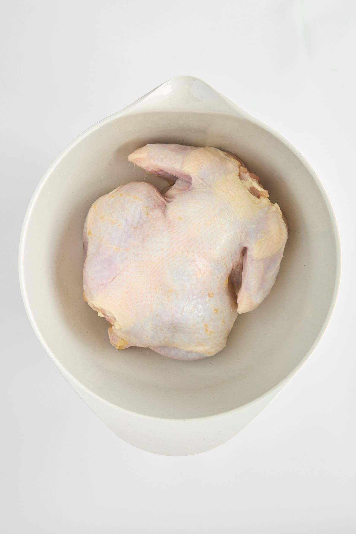 A raw whole chicken in a bowl. 