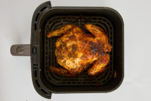 A whole cooked chicken in an air fryer.