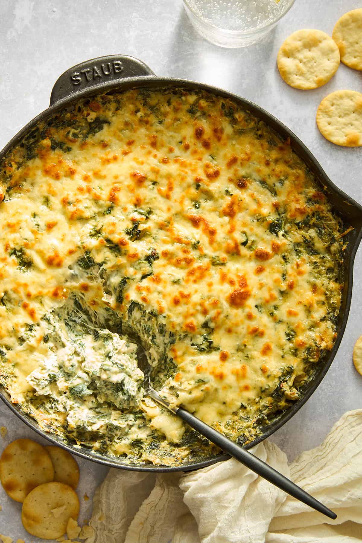 A skillet of creamy chicken spinach and artichoke dip. 