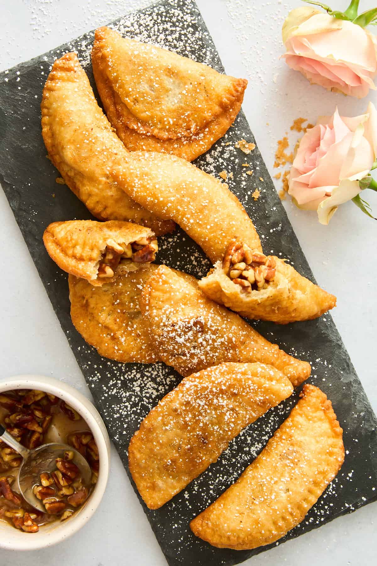 Mini fried pecan pies dusted with powdered sugar.