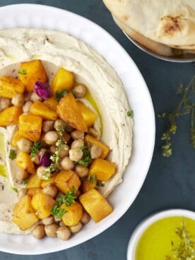 a bowl of roasted maple butternut squash hummus with a bowl of olive oil and pita bread on the side