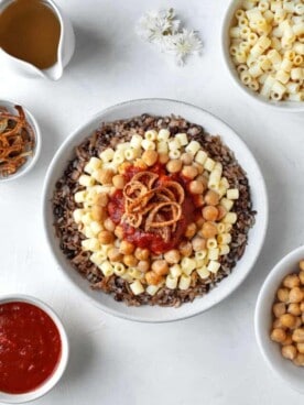 overhead large bowl of koshari with the fixings on top and the sides