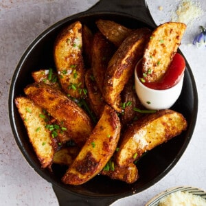Garlic parmesan potato wedges with a small container of ketchup.