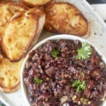 overhead image of a platter with a bowl of easy olive tapenade and toasted crostini