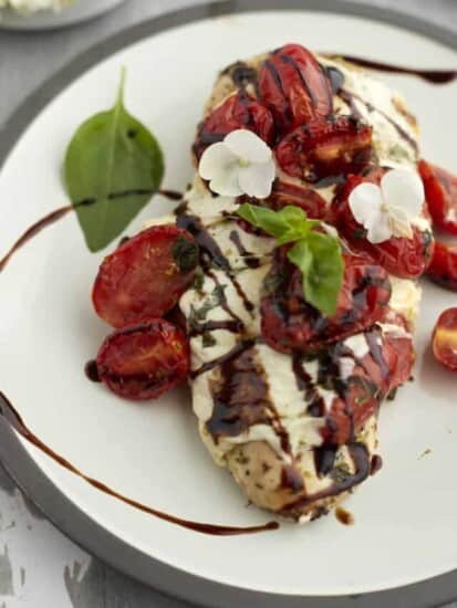 a close up image of baked bruschetta chicken topped with mozzarella, tomatoes, balsamic vinegar, and basil