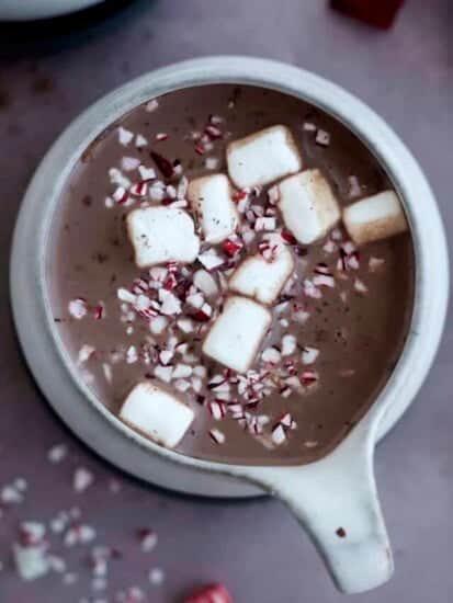 overhead image of a mug of hot chocolate topped with marshmallows and candy cane pieces