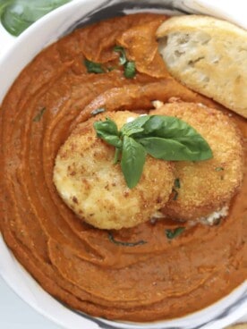 overhead image of a bowl of fried burrata with romesco sauce with a piece of bread dipped in