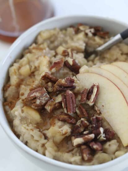 a bowl of apple cinnamon oatmeal topped with pecans and sliced apples