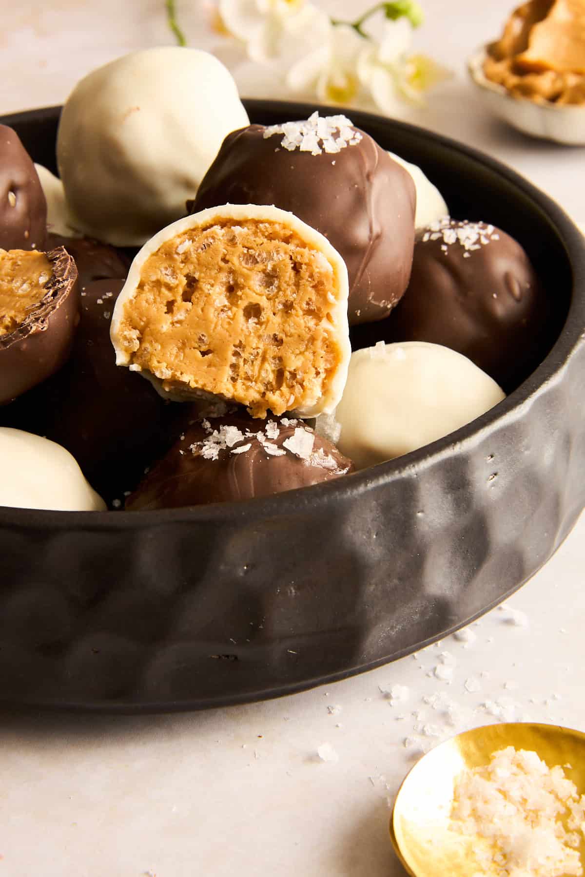 A bowl of Peanut Butter Balls with Rice Krispies with one missing a bite. 