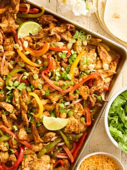 Sheet pan chicken fajitas topped with lime wedges.