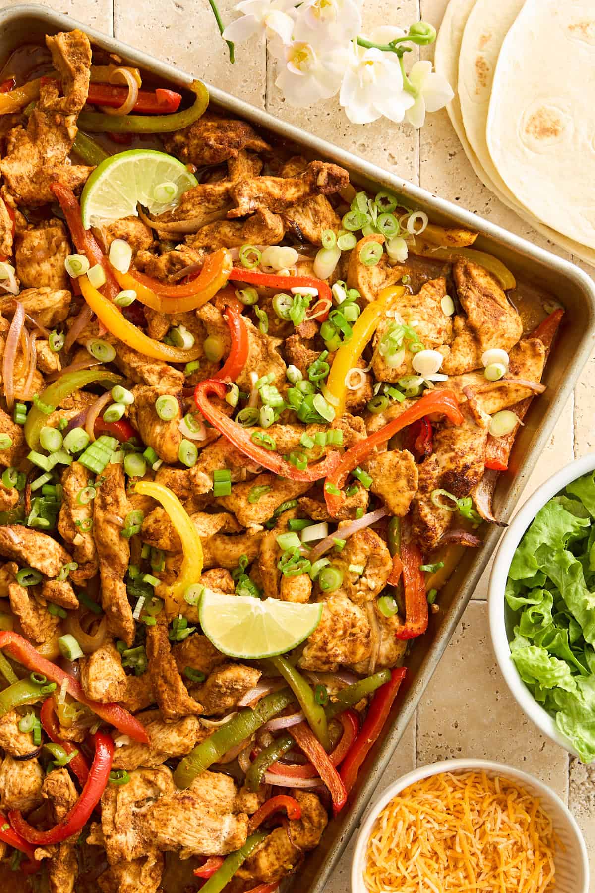 Sheet Pan Chicken Fajitas on a baking sheet topped with lime wedges. 