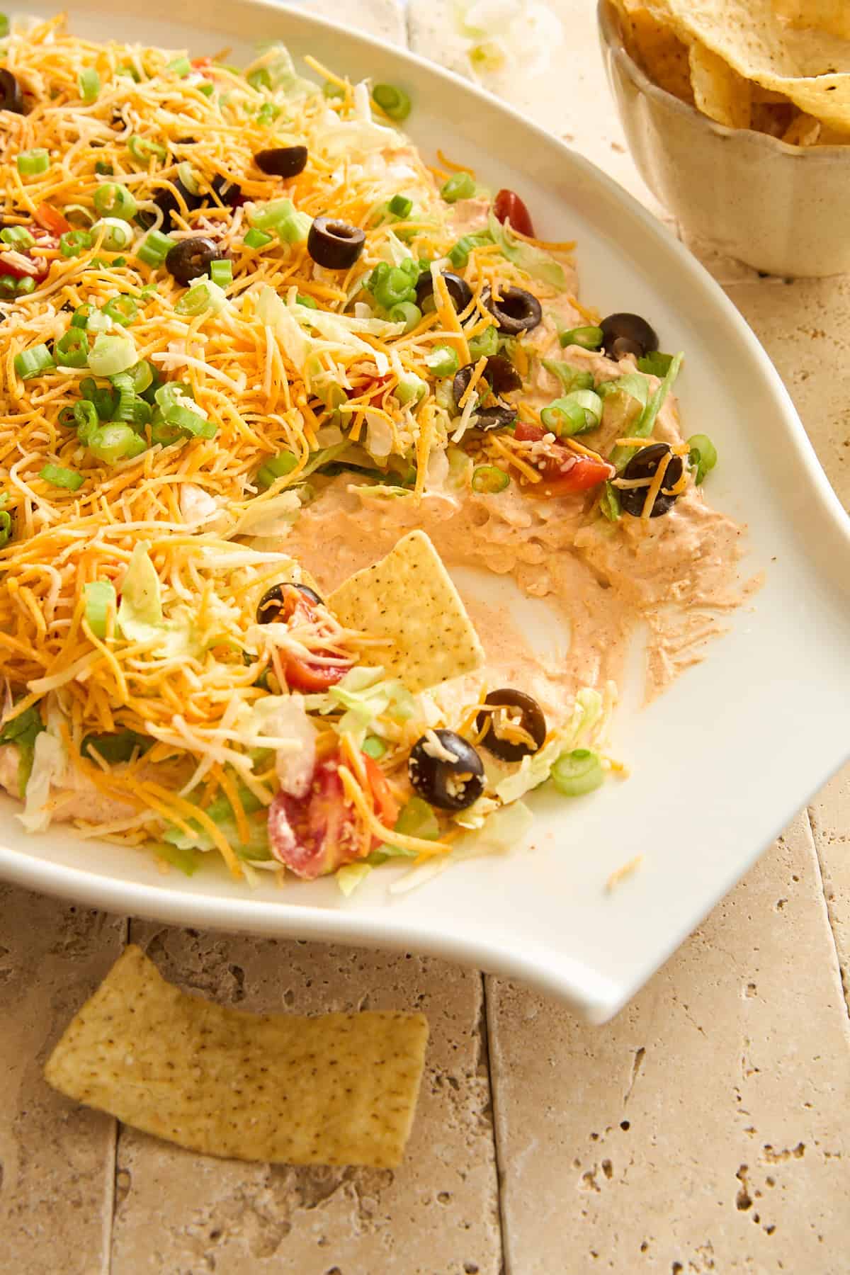 A platter of layered taco dip with a tortilla chip sticking out. 