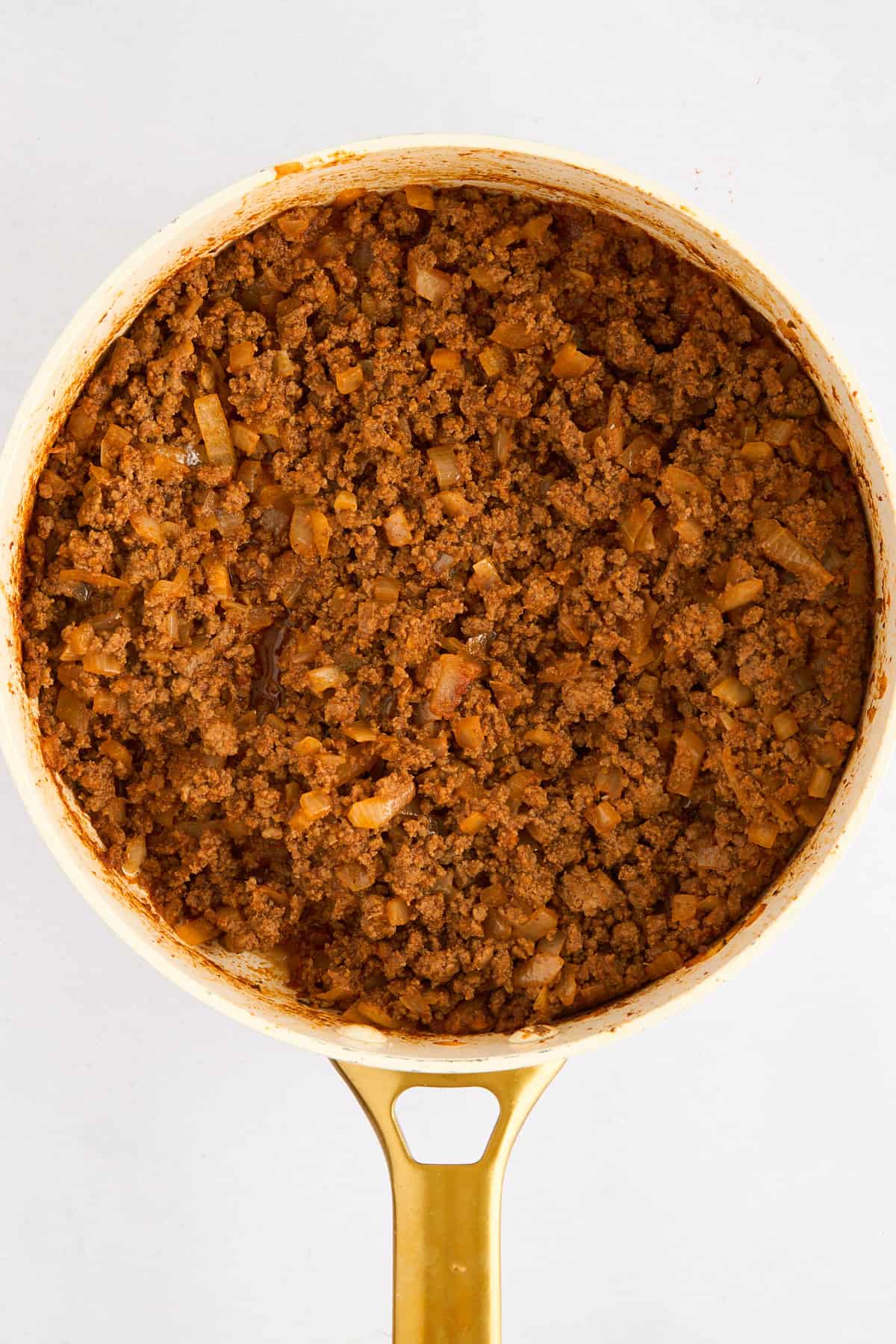 Cooked ground beef with tomato paste, spices, and onions in a pot.