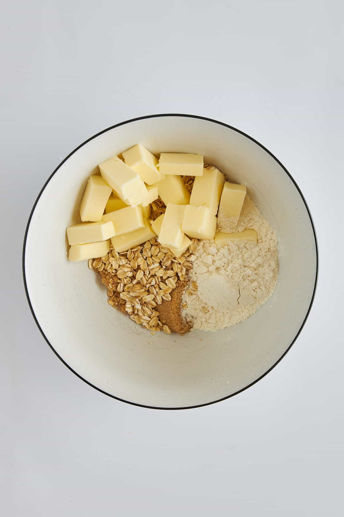 Butter, oats, flour, and sugar in a bowl. 