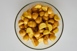 Seasoned Greek potatoes in a mixing bowl.