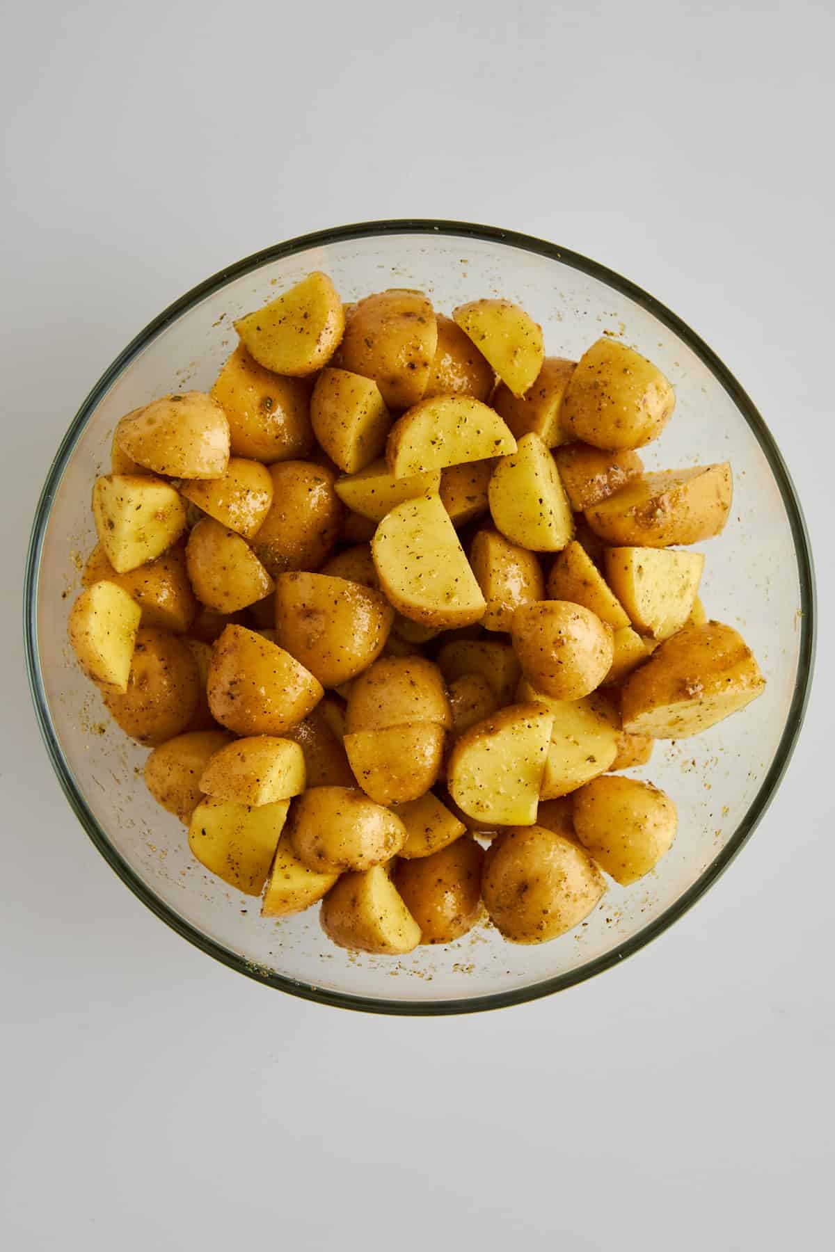 Seasoned golden potato pieces in a mixing bowl. 