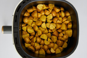 Uncooked Greek potatoes in an air fryer basket.