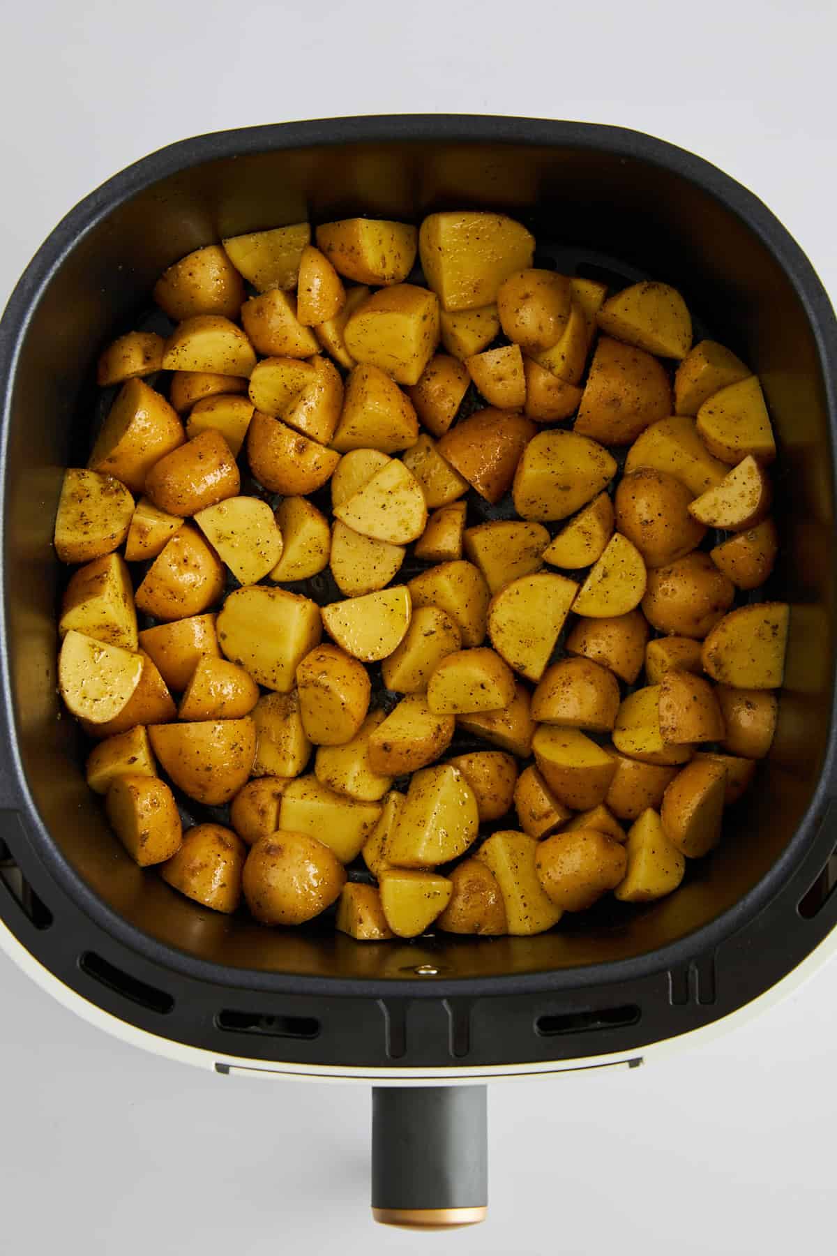 Uncooked Greek potatoes in an air fryer. 