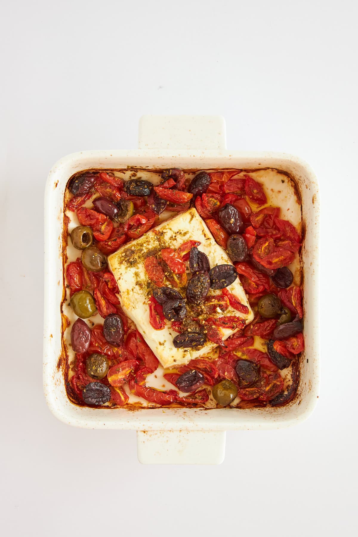 Overhead image of baked feta dip with olives and peppers. 