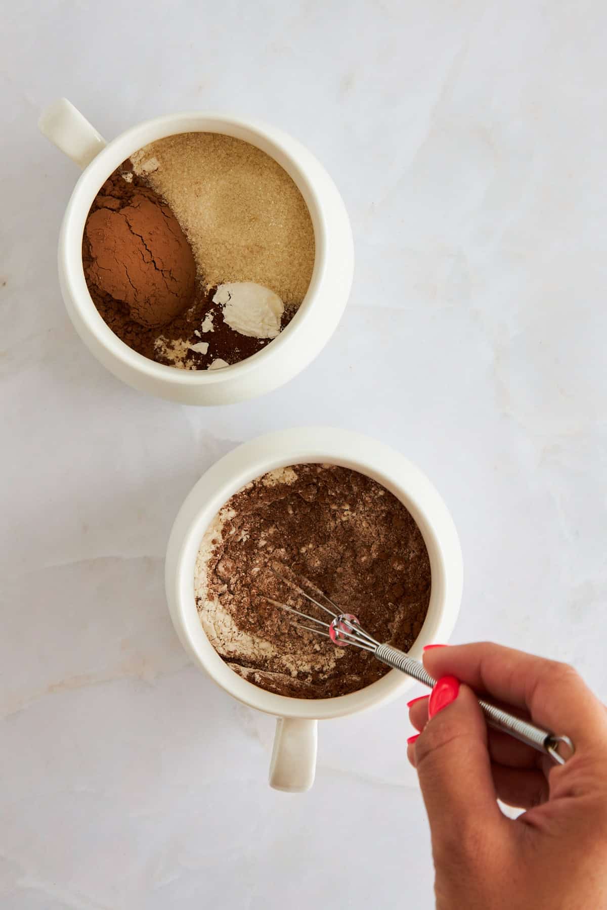 Chocolate mug cake ingredients being whisked in mugs. 