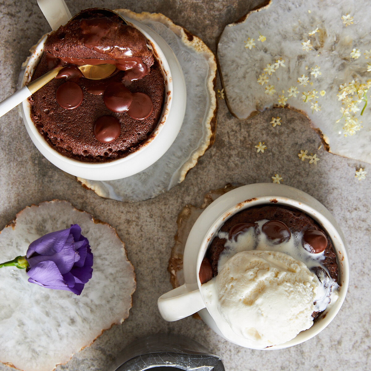 Overhead image of two chocolate mug cakes, one with a spoon sticking out the other topped iwth ice cream.