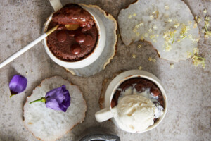 Overhead image of two chocolate mug cakes, one with a spoon sticking out the other topped iwth ice cream.