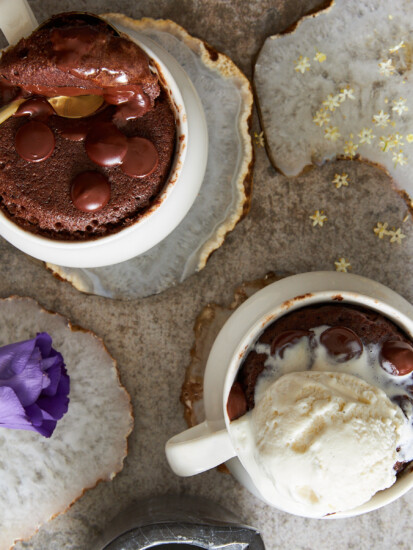 Overhead image of two chocolate mug cakes, one with a spoon sticking out the other topped iwth ice cream.