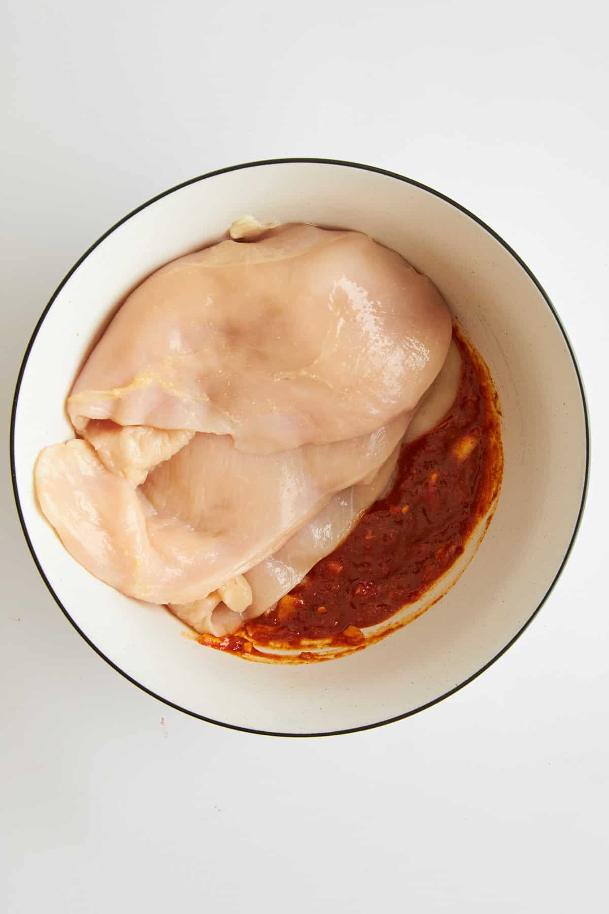 Raw chicken and honey harissa marinade in a bowl. 