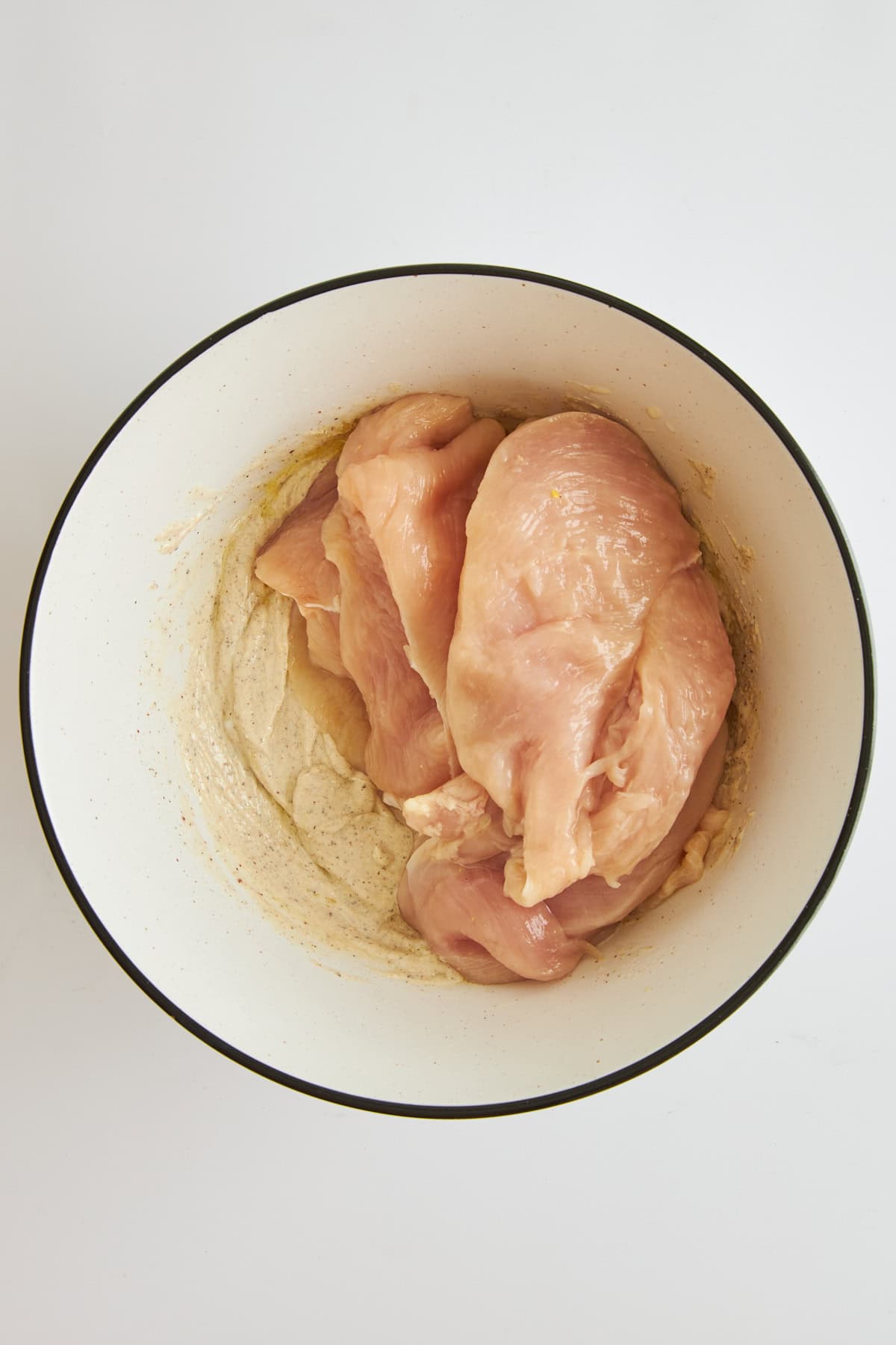 Raw chicken and tahini yogurt marinade in a bowl. 