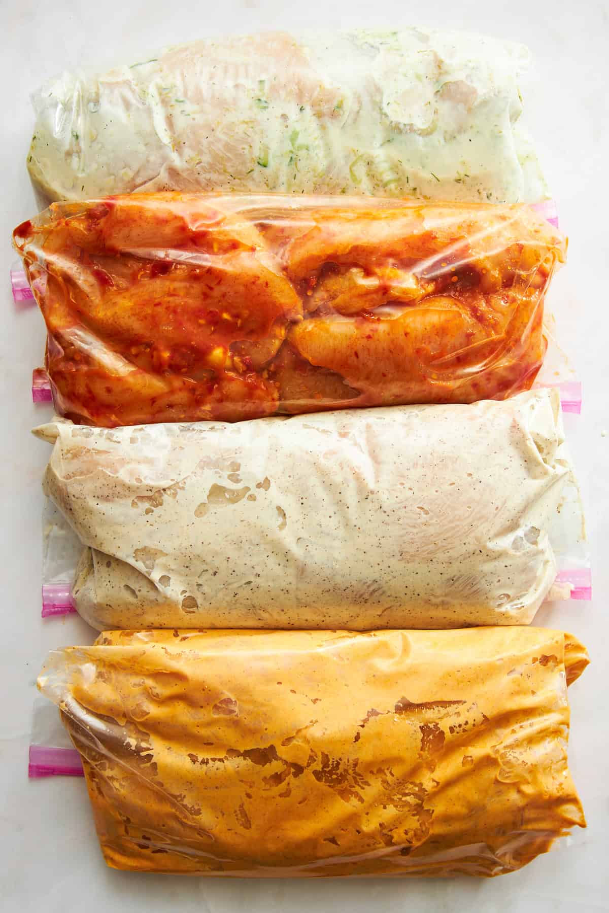 Four bags of chicken marinading in different flavors. 