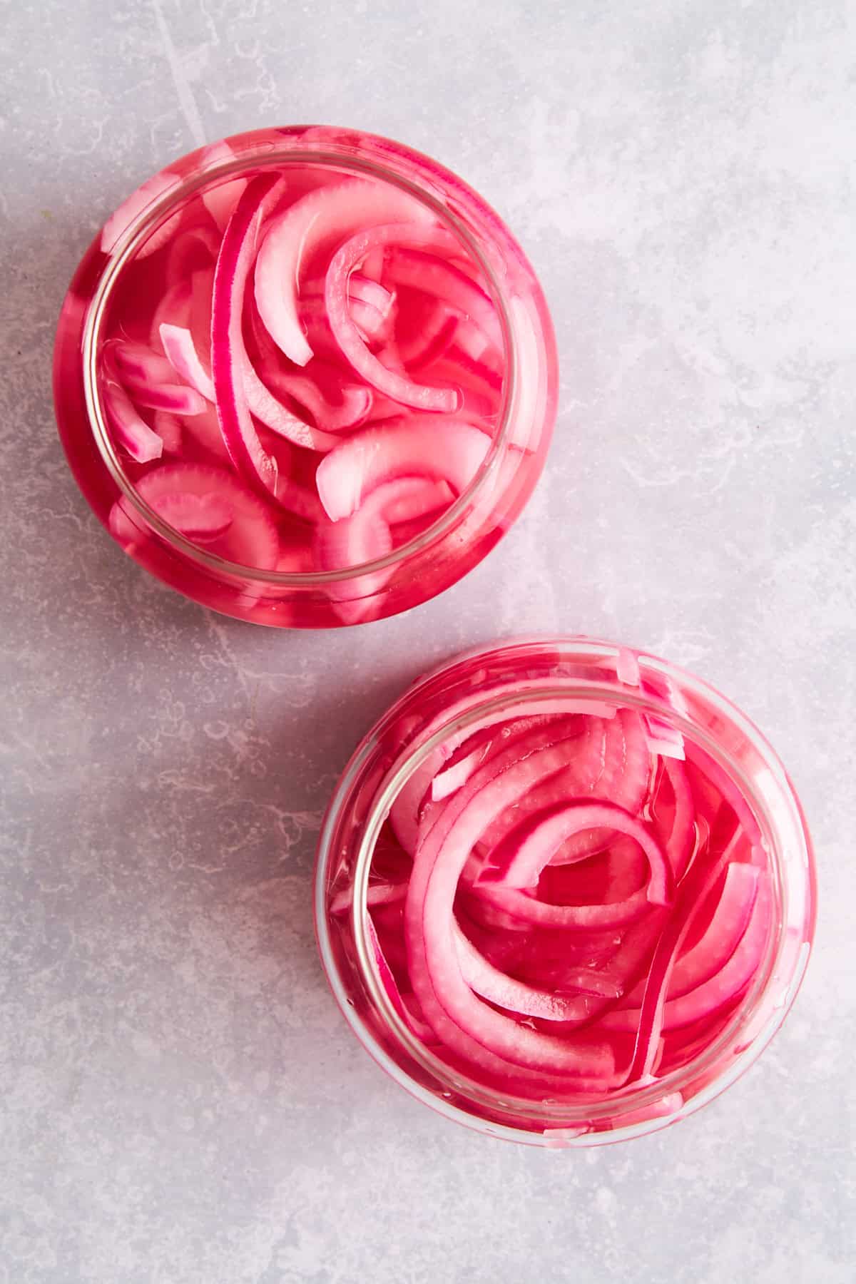 Overhead image of two jars of pickled red onions. 