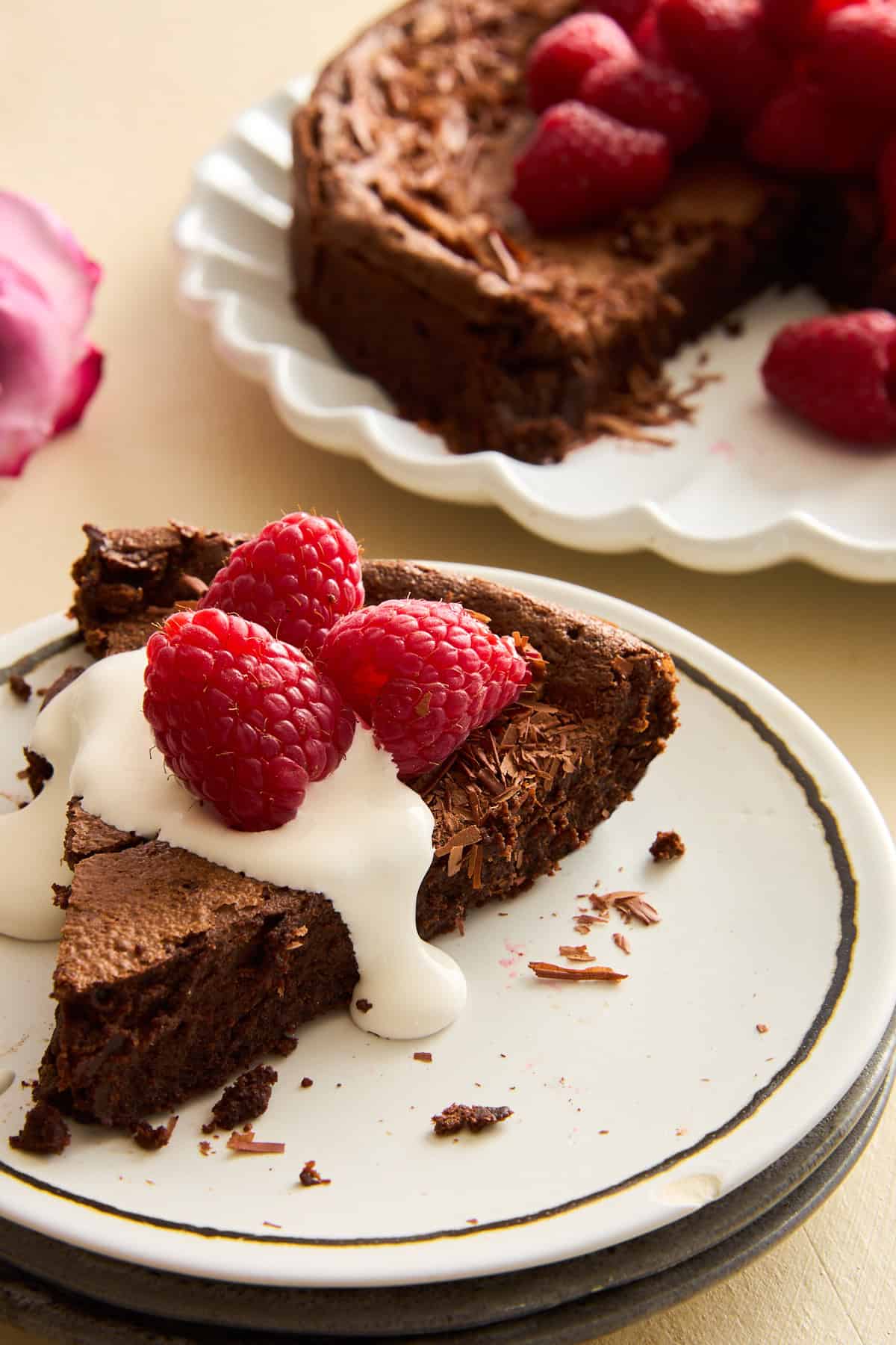 A slice of flourless chocolate cake topped with cream and raspberries. 