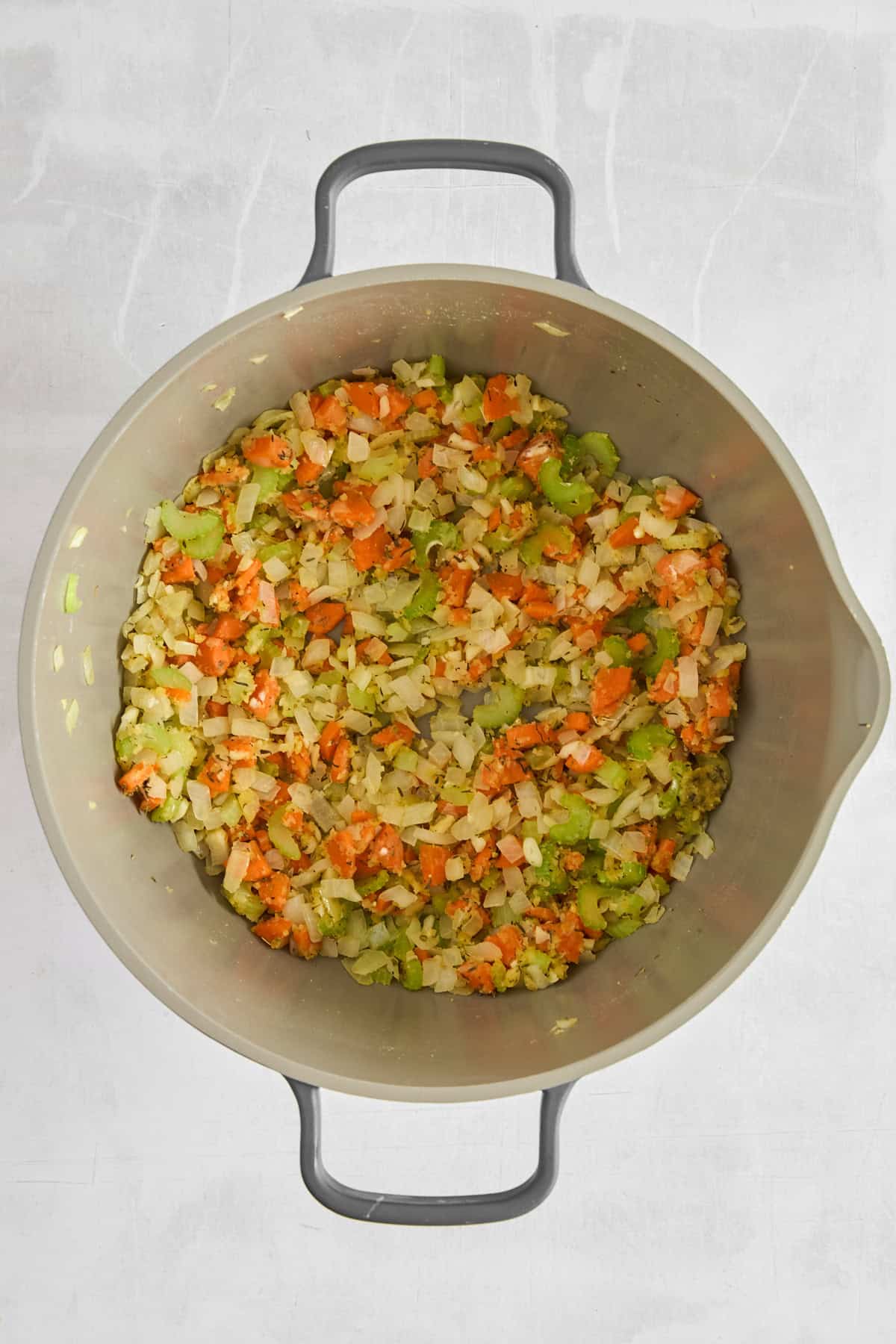 Onions, carrots, and celery sautéing in a pot. 