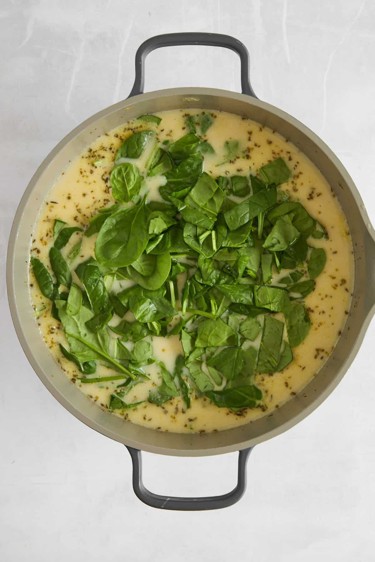 Fresh spinach wilting in a pot of chicken and gnocchi soup. 