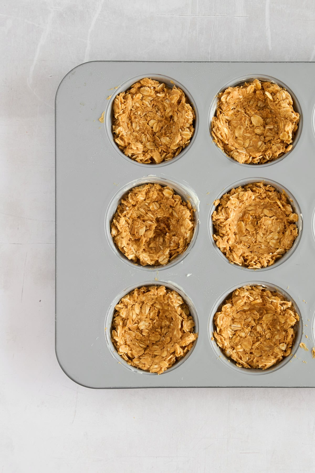 Unbaked granola cups in a muffin tin. 