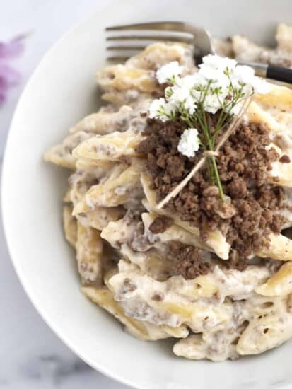 One Pot Macarona Bechamel in a white pot topped with white flowers for garnish