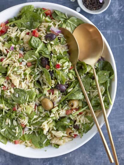 overhead of greek orzo pasta salad with serving spoons