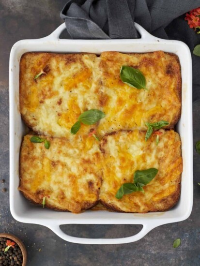 four baked easy chicken fajita sandwiches topped with golden cheese in a square white baking dish.