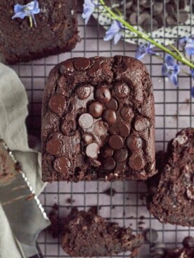 half a loaf of double chocolate banana bread on a wire rack with a knife in the bottom lefthand corner