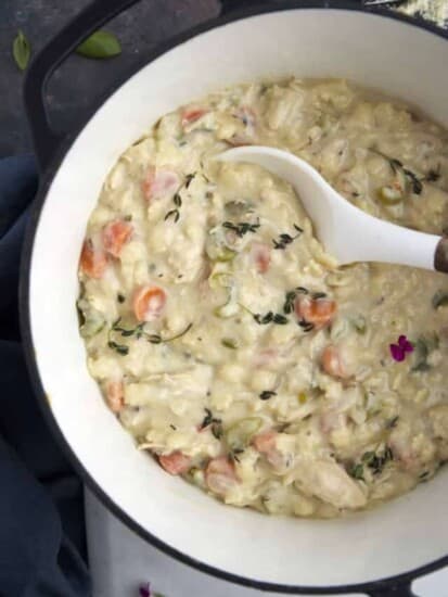 a bowl of creamy chicken noodle soup being scooped up with a spoon