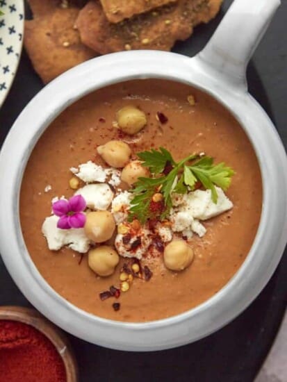 a bowl of Moroccan spicy tomato soup topped with feta, chickpeas, fresh parsley, and crushed red pepper flakes