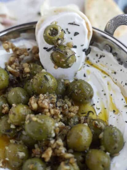 crostini dipped into labne topped with marinated olive and pine nuts