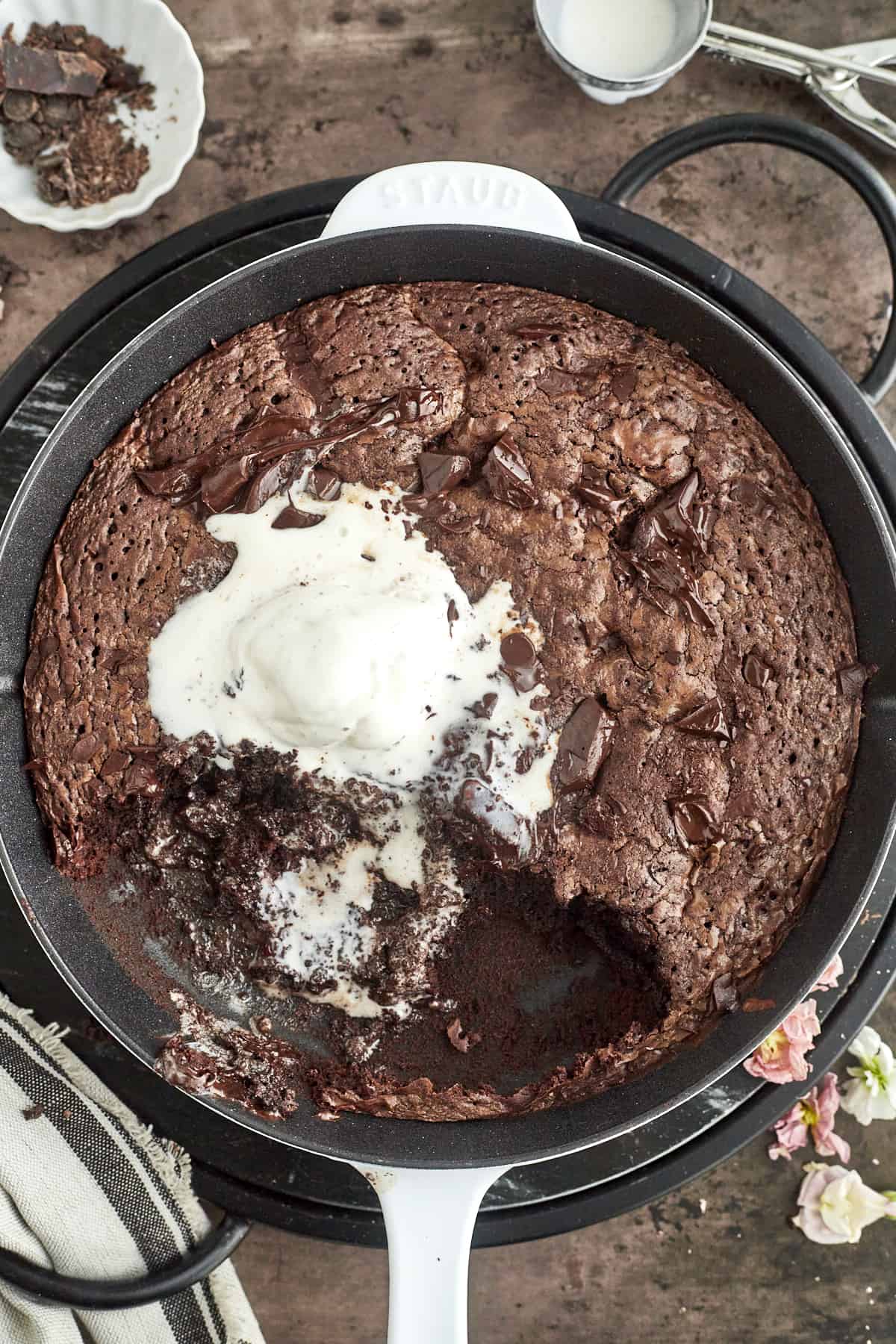 overhead image of a chocolate hazelnut skillet brownie topped with vanilla ice cream