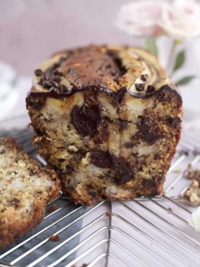 A front view of a sliced loaf of easy banana bread with semi-sweet and white chocolate chips, walnuts, and banana pieces.