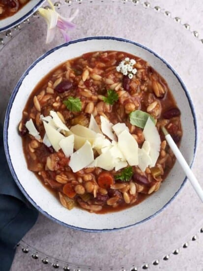 a bowl of Slow Cooker Pasta and Beans Soup (Pasta E Fagioli) topped with Parmesan cheese