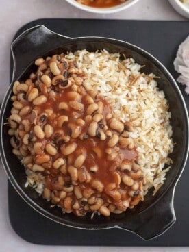 a skillet of vermicelli rice topped with black-eyed pea stew